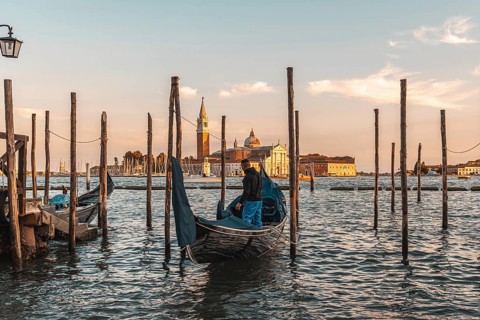 Gondolier preparing his gondola in venice, italy, at sunset, with the church of san giorgio