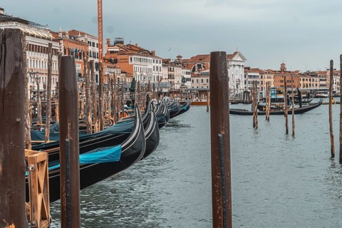 Gondolas moored near the rialto bridge in venice, waiting patiently for tourists on a cloudy day,
