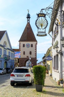 Special sign of the Hotel Pfauen, in the background the Königschaffhausen Tor, an old town gate of