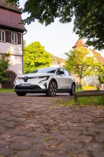 White car on cobblestones in a picturesque village, Renault Megane, Deer E Carsharing, electric