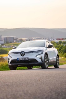 Car driving along a road with a view of modern buildings in the background, Renault Megane, Deer E-