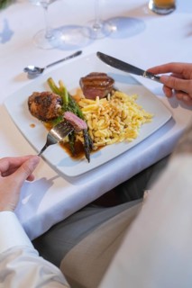 A plate of meat, asparagus and spaetzle on a white table with cutlery, event and wedding location