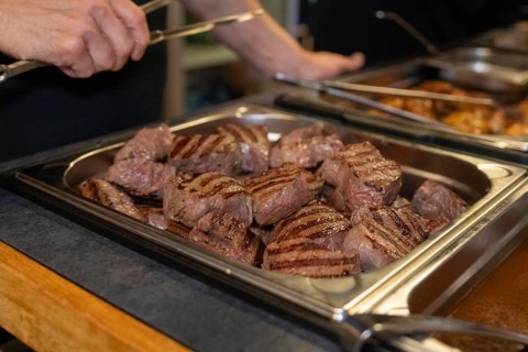 Several pieces of grilled meat in a buffet tray in a kitchen, ready to serve, event and wedding