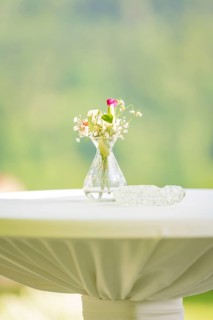 White table with a small flower vase and an ashtray in front of a blurred background, event and