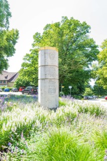 Stone monument surrounded by blooming summer meadows and green foliage, event and wedding location