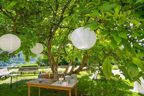 Summer garden with table, crockery and decorative white lanterns under a tree, event and wedding