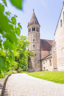 Medieval church tower next to a tree-lined green path on a summer's day, event and wedding location