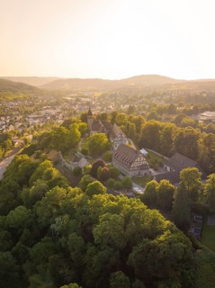 Aerial view of a historic castle surrounded by wooded hills at sunset, event and wedding location