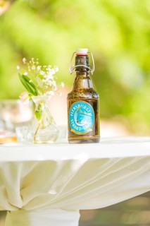 Table with a beer bottle and flower vase outside on a sunny day, event and wedding location Kloster