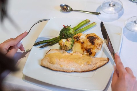 An elegant plate with fish, asparagus and broccoli on a laid table, event and wedding location