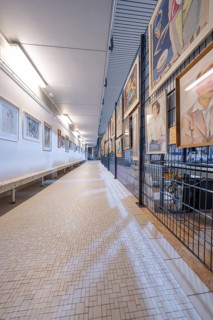 Long corridor in a gallery, lined with works of art on the walls, historical art exhibition in the