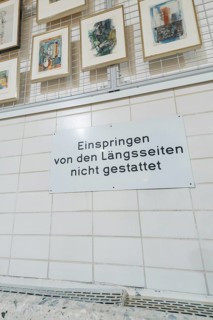 Sign on a tiled wall in a gallery with works of art on display, historical art exhibition in the