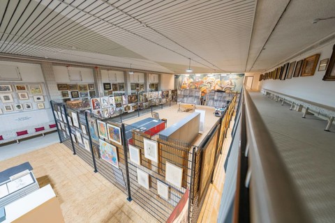View of a diverse collection of artworks in a modern gallery on an upper floor, historical art