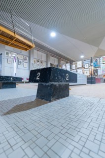 A dark winner's podium stands in an exhibition hall, surrounded by works of art and industrial