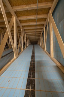 View into an attic with wooden struts and blue tiled floor leading into the distance, historical
