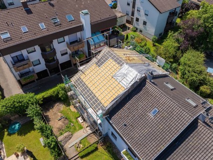 Several houses in the neighbourhood. A roof is under construction with scaffolding, sunny weather,