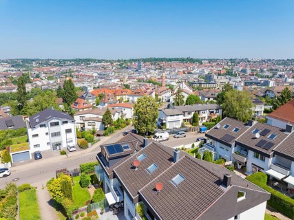 Bird's eye view of a residential neighbourhood with tiled roofs against an urban backdrop, roof