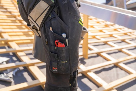 Construction worker on roof construction with tools in his trouser pocket, roof renovation, house