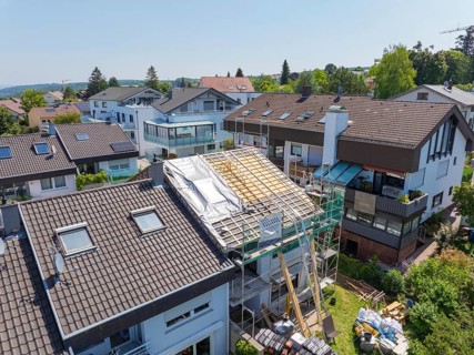 House with scaffolding and partially open roof in a suburban residential area, roof renovation,