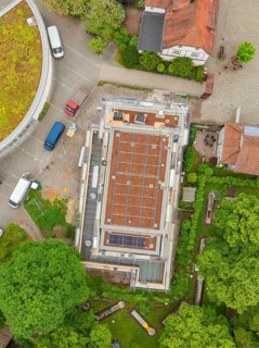 Building with visible roof in the construction phase, surrounded by vehicles and trees, Hirsau,