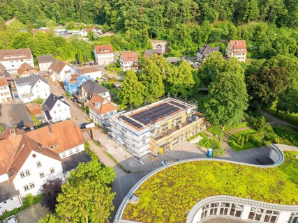 View of a residential area with a building site in the centre and green areas on some roofs,