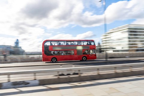 Red double decker bus driving across london bridge, capturing the essence of london's vibrant
