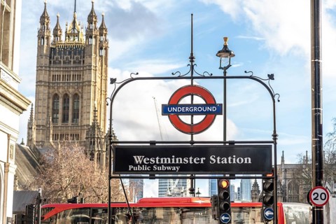 Westminster underground station sign with the houses of parliament, including the victoria tower,