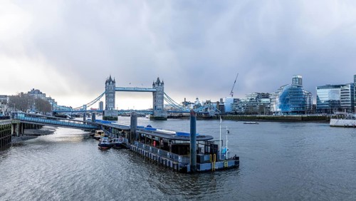 Tower bridge rising above river thames with city hall and modern buildings in background, capturing