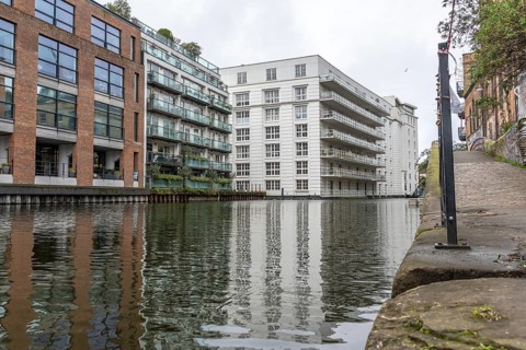 Modern and historic buildings reflecting in the calm waters of regent's canal in the city of london