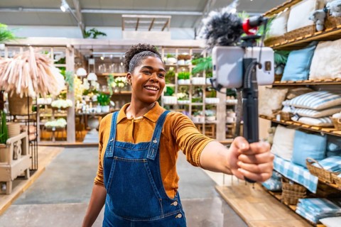 Smiling influencer recording video content with smartphone and microphone for social media
