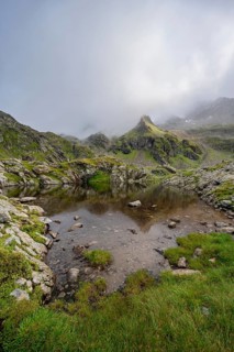 Small mountain lake, cloudy mountain peaks reflected in the lake, Schober group, Hohe Tauern