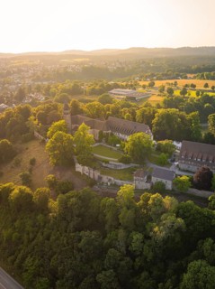 Aerial view of a monastery surrounded by dense vegetation at sunset, event and wedding location