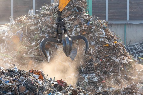 Hydraulic crane lifts scrap metal at the scrap yard