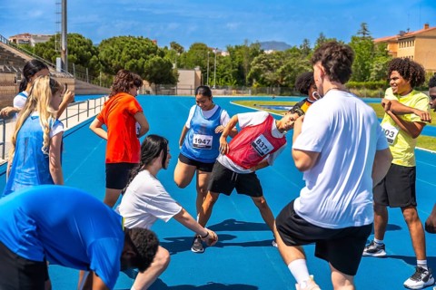 Teenage athletes stretching their legs and arms on a vibrant blue track, engaging in warm up