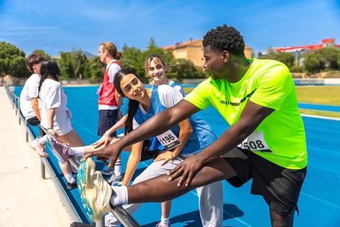 Runners stretching their legs on a sunny running track, preparing for an upcoming race and