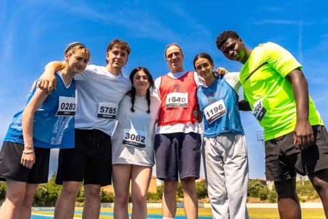 Group of young athletes embracing after a track and field competition, showing sportsmanship and