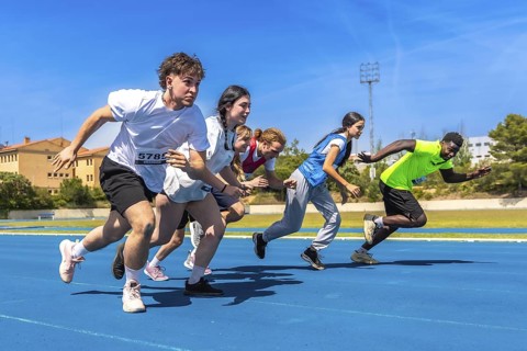 Diverse group of athletes sprinting on a vibrant blue running track under a bright sun, showcasing