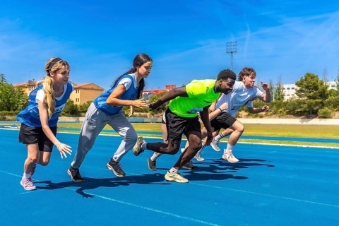 Young athletes sprinting energetically on a vibrant blue track under the bright sun, showcasing