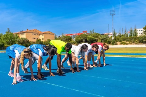 Diverse group of athletes ready to start a race on a blue running track, embodying competition and