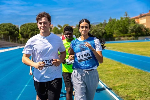 Group of athletes running on a blue track during a sports competition, demonstrating teamwork and