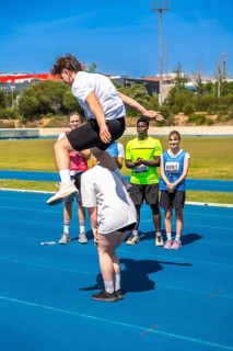 Young athlete jumps over a teammate on a track, showcasing teamwork and athleticism during a track