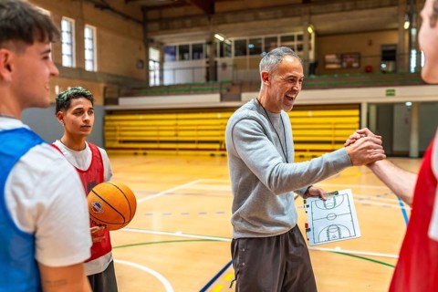 Basketball coach shaking hands with a player and congratulating him after a training session in a