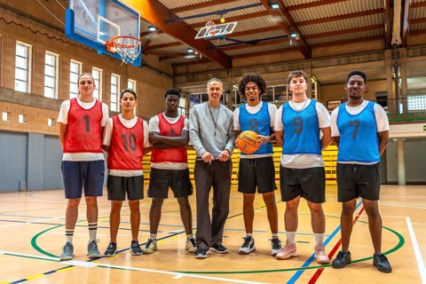 Multi ethnic basketball team and their coach standing together on the court after a training