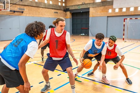 Young basketball players practicing in a gym, focusing on defense and attack strategies during a