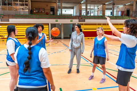 Female basketball coach explaining game strategy to her team during training session in a gymnasium