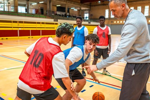 Basketball coach guiding young players, explaining tactics and positions on the court during