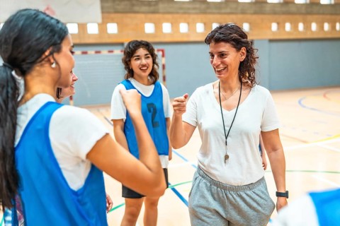 Female basketball coach motivating her team during training, encouraging players and giving support