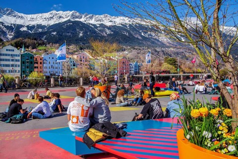Sun-seekers on the market square on the banks of the Inn in front of the Nordkette mountain range