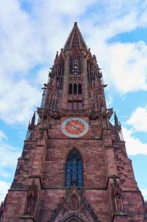 Freiburg Minster, Gothic church tower made of red stone with clock in front of a blue sky, Freiburg