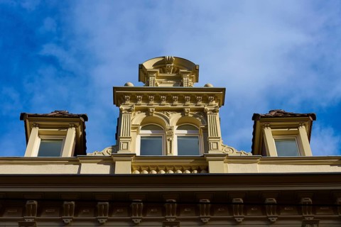 Decorative façade of a historic building with windows and baroque details under a blue sky,